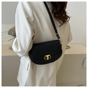 Detail shot of the black leather shoulder bag showcasing its elegant gold lock clasp and strap.