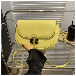 Detailed shot of yellow leather saddle bag showcasing the metal lock and fine shoulder strap.