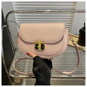 Pink saddle crossbody bag with chic metal lock and adjustable shoulder strap detail.