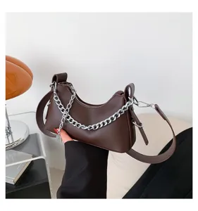 Dark brown leather underarm bag detail, featuring a silver chain decoration and strap.