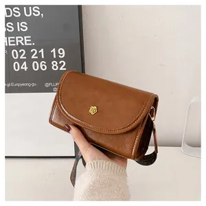Detailed view of brown PU leather crossbody bag with vintage wide strap and gold flower clasp.