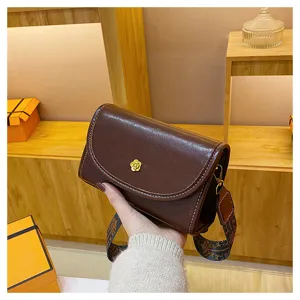 Brown leather crossbody bag for women, stylish small square bag with wide patterned strap.