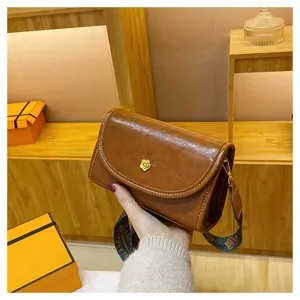 Detailed view of niche design brown shoulder bag with contrast stitching and wide strap.
