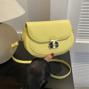 Stylish yellow saddle shoulder bag for women, elegant leather crossbody bag with chic metal lock.