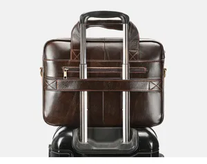 Dettaglio ravvicinato della pratica cinghia per trolley sulla borsa in pelle marrone.