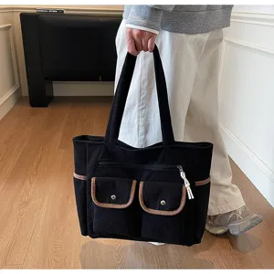 Details of the black corduroy tote bag with multiple pockets and contrast trim for daily use.