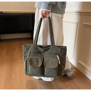 Green corduroy tote bag detail showing multi-pocket design, front flap pockets and sturdy handles.