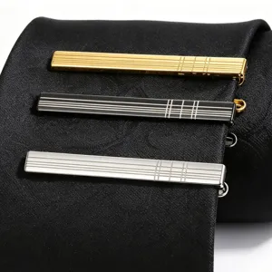 Detailed closeup of three stylish metal tie clips featuring engraved grid patterns on a black tie.