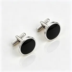 Closeup of silver metal cufflinks with black round inlay, elegant detail for dress shirts.
