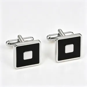 Close-up of square silver-tone cufflinks featuring black enamel inlay and polished center detail.