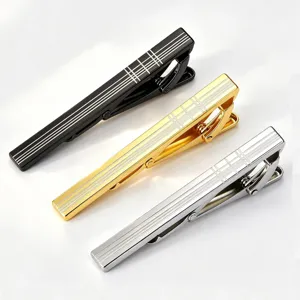 Close up view of luxury metal tie clips featuring laser engraved grid patterns in black, gold and