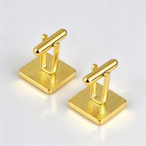 Gold square cufflinks detail close-up, grid textured metal surface and bullet-back closure.