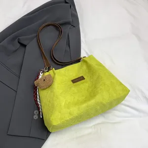 Elegante borsa tote trapuntata verde lime con manici marroni e ciondolo orsetto per uso quotidiano.