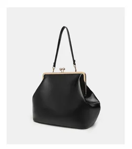 Detailed close-up of the elegant black leather kiss-lock handbag featuring a shiny metal frame.