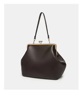 Close-up detail of the dark brown kiss-lock frame handbag showcasing premium texture.