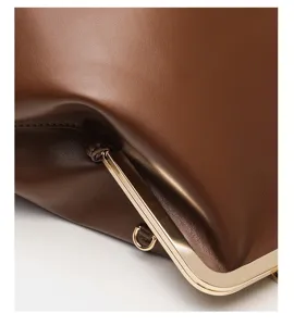 Detailed view of brown leather clutch bag with metallic kiss-lock frame and soft texture.