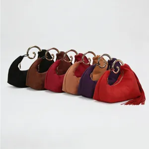 Detailed view of vintage suede handbag featuring a unique gold swirl handle and elegant fringe tassel.