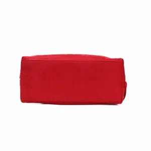 Red suede handbag bottom detail view, premium soft texture, elegant tassel design accent.