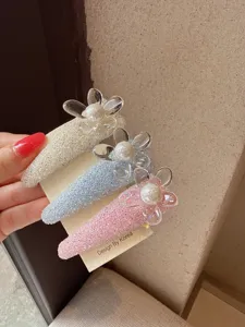 Close-up of sparkly rhinestone flower hair clips with pearl centers on card display.