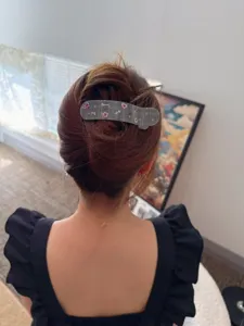 Detail shot of stylish grey plaid hair claw clip worn on bun, elegant design with cute accents.