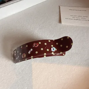 Detailed view of brown acetate polka dot hair claw clip with cute charms for daily styling.