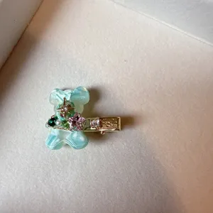 Close-up of cute green acetate bear hair clip with sparkling rhinestones and metal duckbill.
