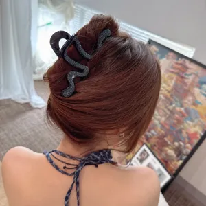 Detail shot of a black rhinestone geometric hair claw clip styling on back updo hair.