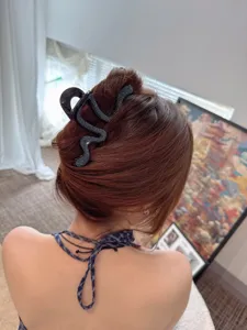 Detail shot of a black rhinestone snake hair claw clip worn on the back of the head.