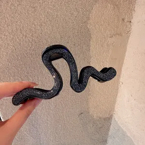 Close-up detail of a black rhinestone snake hair claw clip showcasing unique texture.