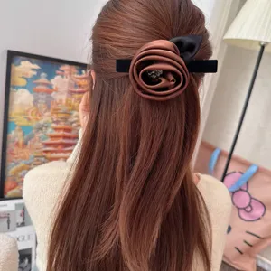 Detail shot of a retro brown satin rose hair clip with sparkling rhinestones and black bow.