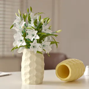 Vue détaillée d'un vase en céramique facetté géométrique avec de beaux lys artificiels.