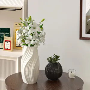 Detailed view of modern minimalist white ceramic wave vase with fresh white lilies on a wooden table.