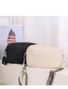 Detailed view of fashionable pebble grain PU leather crossbody bags with trendy wide striped straps.