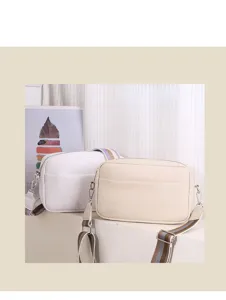 Detailed view of women PU leather crossbody bags with wide straps in white and beige.