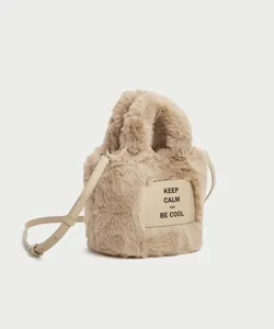 Plush bucket bag detail view, soft faux fur texture, adjustable leather strap, front label.