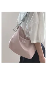 Detailed view of the stylish canvas shoulder bag worn on shoulder, showing casual daily look.