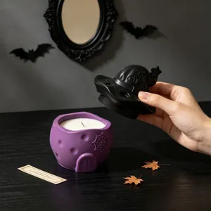 Halloween scented candle in purple house container with black witch hat lid and web.