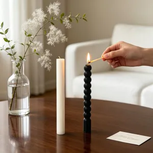 Minimalist aesthetic black and white pillar candles lifestyle detail shot on wooden table.