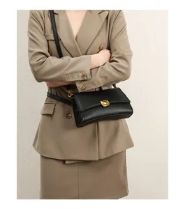 Detailed view of urban black baguette shoulder bag featuring gold hardware and sleek strap design.