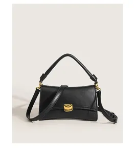 Detail view of the elegant black underarm baguette bag featuring luxury gold-tone metal hardware.