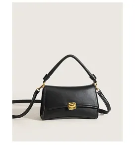 Detailed view of the black chic baguette shoulder bag with gold-tone metal clasp and handle.