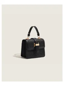 Detailed view of the black woven square bag with elegant gold metal T-bar clasp hardware.