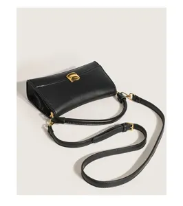 Black fashion underarm baguette bag detail view, showing exquisite gold hardware.
