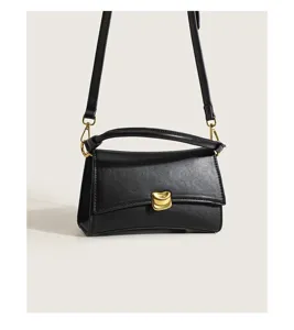 Black leather underarm bag detail showing golden hardware clasp and sleek texture curve.
