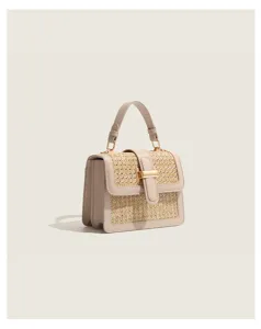 Woven straw textured flap detail with elegant gold tone metal closure on stylish handbag.
