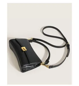 Close-up detail of the black leather baguette bag featuring a chic golden clasp and shoulder strap.