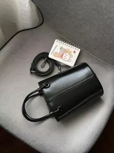 Black bucket bag detail shot, simple PU leather handbag with shoulder strap for women.