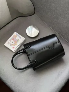 Black minimalist bucket bag for women, stylish leather handbag with top handle and chic design.