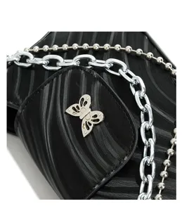 Close up detail of black textured shoulder bag with silver chains and butterfly accent.