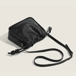 Black leather shoulder bag with chic pleated design and stylish knotted strap for women.